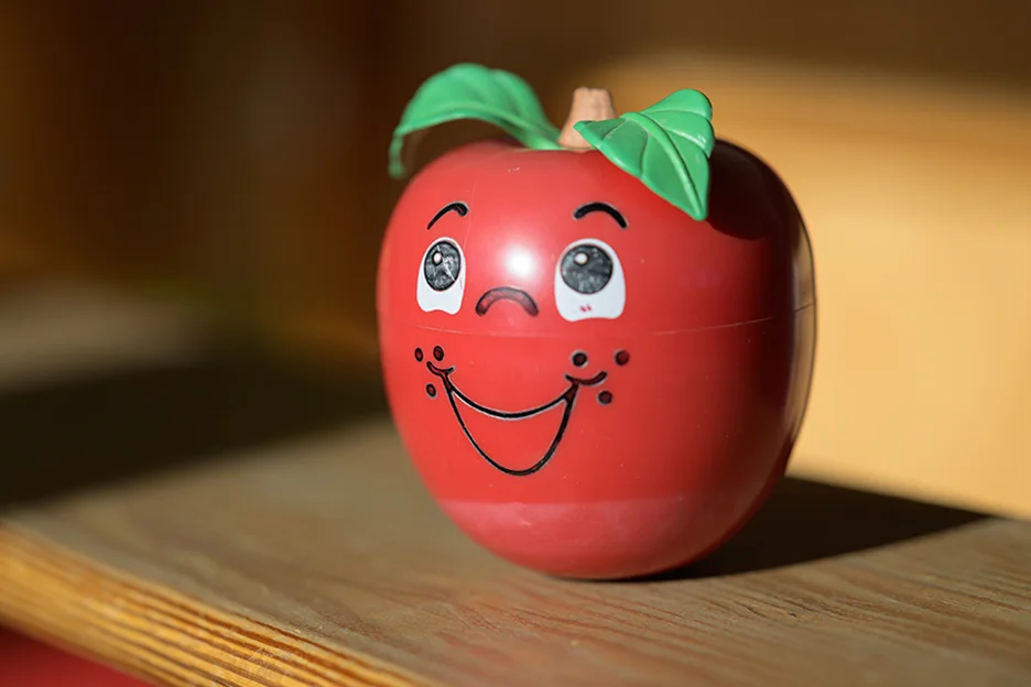 Eine grinsende rote Tomate steht auf einem Holzregal