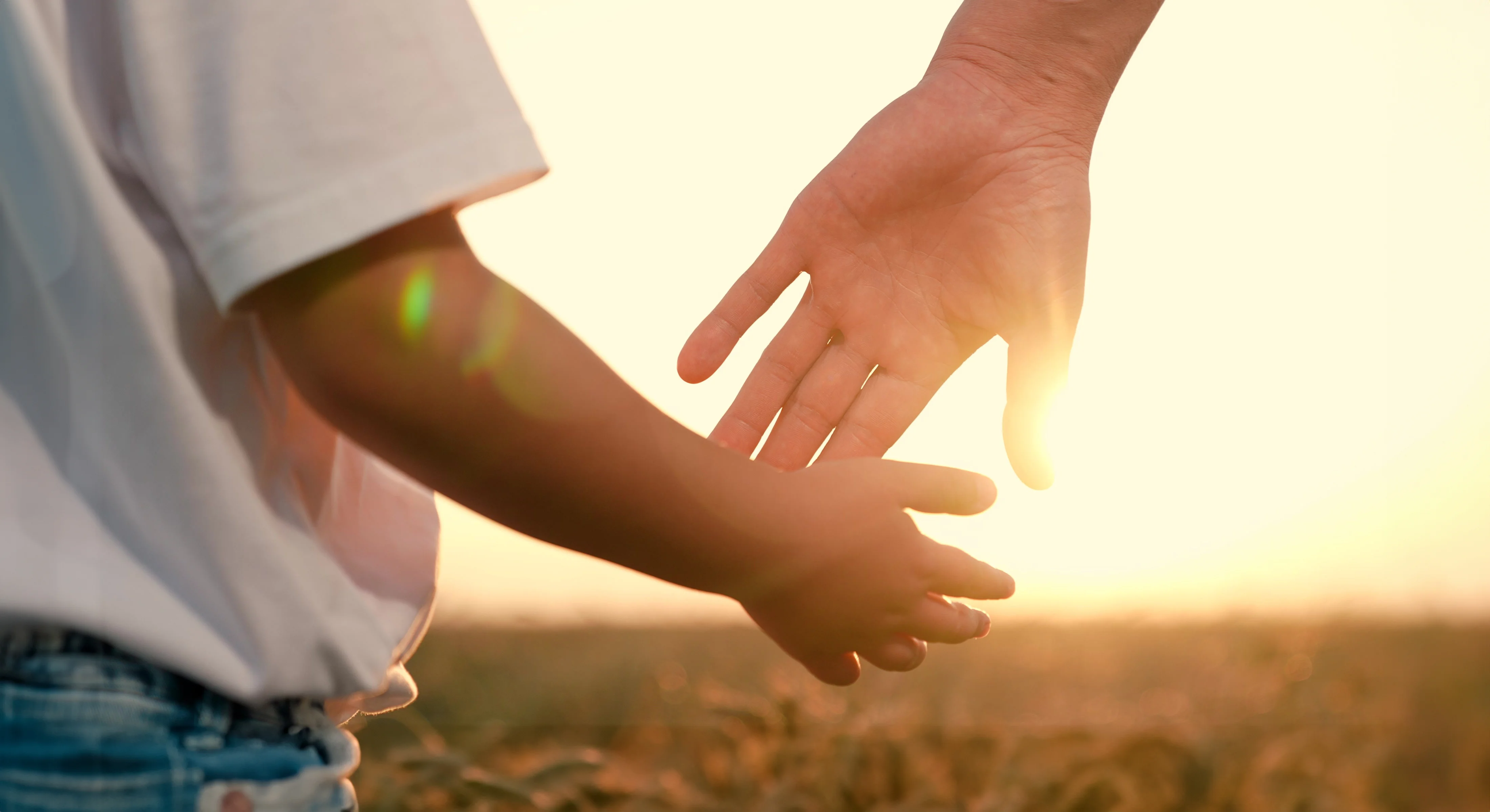 Kleinkind hält Mutter an der Hand im Sonnenlicht